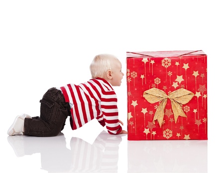 sweet and funny shot of a baby boy in red t-shirt playing with two big christmas gift box. baby on all fours near the big gift boxの写真素材