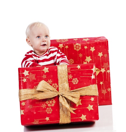 sweet and funny shot of a baby boy in red t-shirt playing with two big christmas gift box. baby is sitting behind the small gift boxの写真素材