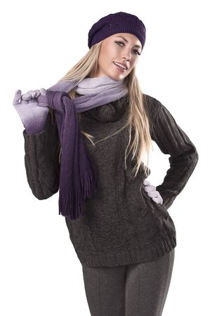 fashion shot of a beautiful blonde wearing a knitted cap, a scarf and gloves to grey sweater and pantsの写真素材
