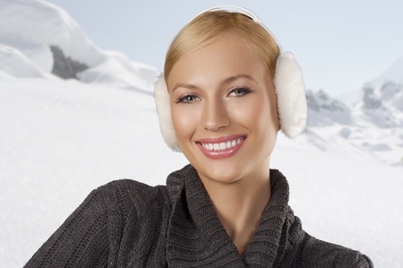 young pretty woman wearing white earmuffs and gray wool sweater be ready to go out in a cold winter day smiling against white backgroundの写真素材