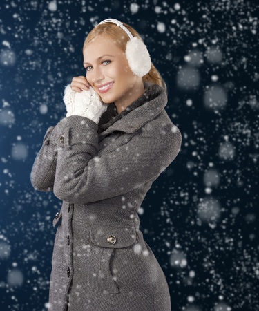 young pretty woman wearing white earmuffs and gray wool sweater be ready to go out in a cold winter day posing against gray backgroundの写真素材