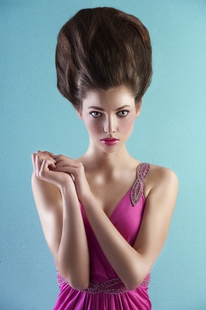 very elegant young pretty wearing a pink long dress with creative hair style over light turquoise backgroundの写真素材