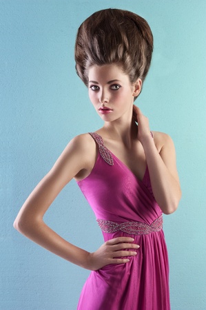 very elegant young woman wearing a pink evening dress and fashion up-do on turquoise backgroundの写真素材