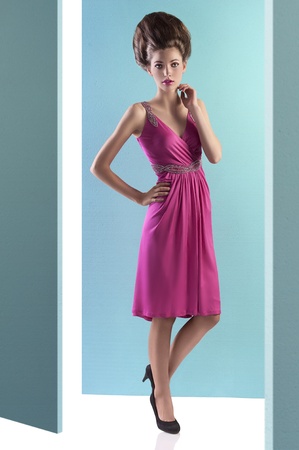 fashion shot of an elegant young woman posing on turquoise background wearing a pink evening dress and a fashion up-doの写真素材