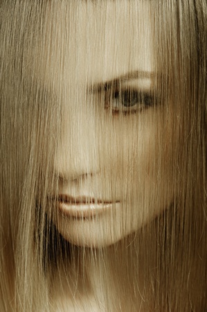 close up of  beauty portrait of a young and cute blond woman with hairstyle and hair covering her faceの写真素材