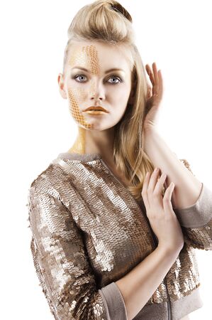 Blond beautiful creature with sequin jacket and creative make up making and hair stylish, she looks in to the lens and her left hand is near the face and  touches the right arm.の写真素材