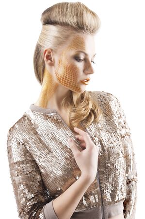 Blond beautiful creature with sequin jacket and creative make up making and hair stylish, she is turned of three quarters, looks down and has the right hand near the chestの写真素材