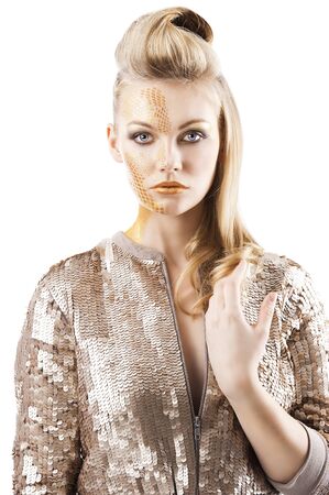 Blond beautiful creature with sequin jacket and creative make up making and hair stylish. She is in front of the camera, looks in to the lens and her left hand is near the chest.の写真素材