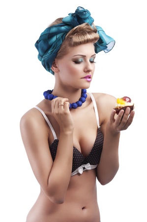 young sexy blond girl with blue head scarf and bra in pin up style holding a ruined pastry and making face の写真素材