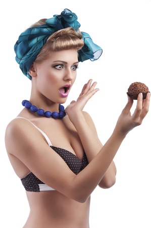 young sexy blond girl with blue head scarf and bra in pin up style holding a big pastry and making surprised  face の写真素材