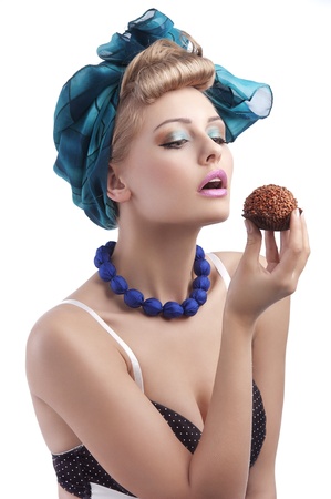 young sexy blond girl with blue head scarf and bra in pin up style eating a big chocolate  pastryの写真素材