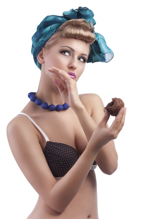 young sexy blond girl with blue head scarf and bra in pin up style eating a big pastry and cleaning lipsの写真素材