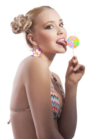 beautiful young woman with blond hair and stylish in bikini swimsuit licking candyの写真素材
