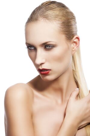 blond pretty woman in a beauty portrait with wet hair and a straight tail over shoulder. She looks down at right, the tail is over the left shoulder and she has a right hand on that.の写真素材