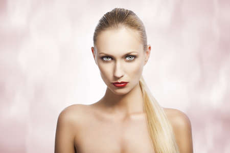 blond pretty woman in a beauty portrait with wet hair and a straight tail over shoulder. She looks in to the lens, the tail is over the left shoulderの写真素材