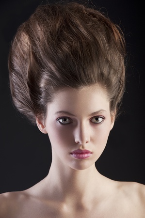 close up portrait of young beautiful woman with dark hair and creative hairstyle posing an black backgroundの写真素材