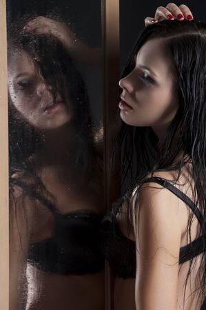 sexy and beautiful girl in black lingerie playing with herself through a dropped mirror with wet hair の写真素材