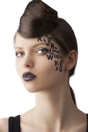 very cute young girl with letter and number painted on her face and a nice creative hair style, she is turned of three quarters at right and looks in to the lensの写真素材