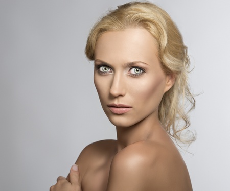 beautiful blonde girl with nudes shoulders and natural makeup, she is turned of three quarters at right, looks in to the lens and her left hand is on the right shoulderの写真素材