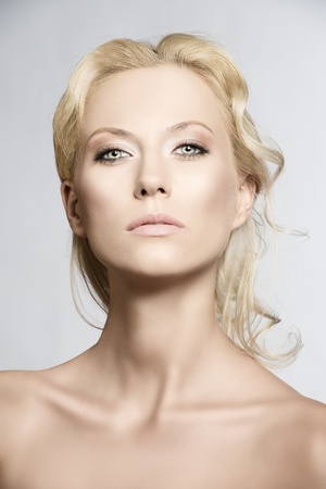beautiful blonde girl with nudes shoulders and natural makeup, she is in front of the camera and looks in to the lensの写真素材