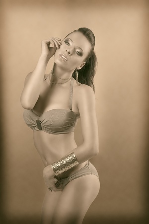 vintage color shot of sexy girl in bikini with brown hair and two gold bracelets, she looks in to the lensの写真素材
