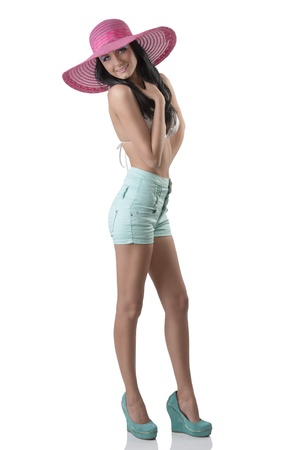 pretty brunette in full lenght with bikini, shorts and big hat. She is turned of three quarters, looks in to the lens and laughsの写真素材