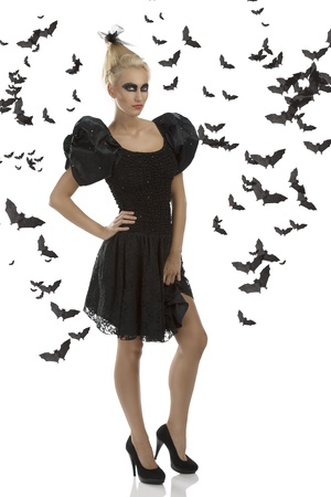 pretty blonde girl with gothic dress and dark make-up, turned of three quarters at left and looks in to the lensの写真素材