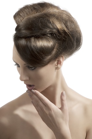 beautiful girl with hair tied in elegant hairstyle, her face is turned at right and her hand is near the mouthの写真素材