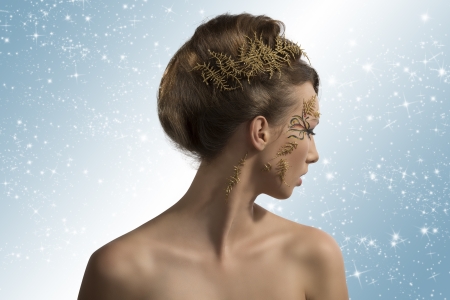 beautiful woman with christmas make-up and hair decoration, her face is turned at left and she looks behind herの写真素材