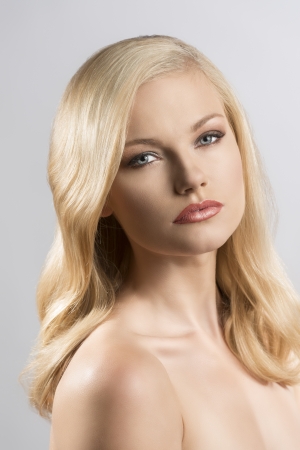 beautiful blonde girl with smooth hair and topless shoulders, her body is turned of three quarters at left and she looks in to the lensの写真素材