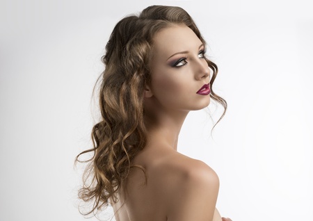 pretty girl with long wavy hair and purple make-up, she is turned of three quarters at left and looks up in front of herの写真素材