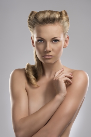 pretty blonde girl with nude torso and creative hair style, she looks in to the lens and her right hand is near the left shoulderの写真素材