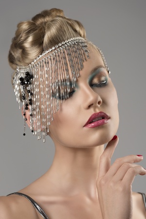 portrait of pretty girl with the elegant hair style and indian decoration on the head, her eyes are closed and has on hand near the chinの写真素材