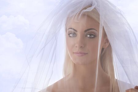 pretty blonde bride with white veil con the face, she looks in to the lensの写真素材