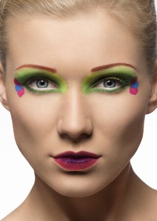 blonde girl with coloured make-up, she is in front of the camera and looks in to the lensの写真素材