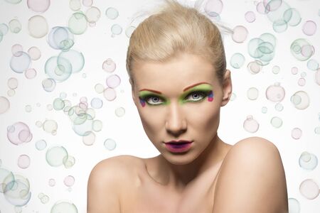 blonde girl with coloured make-up, she looks in to the lens and has naked shoulderの写真素材