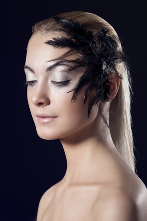beauty portrait of blonde girl with feathered accessory on the face, turned of three quarters and looks downの写真素材
