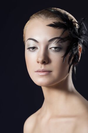 beauty portrait of blonde girl with black feathered accessory on the faceの写真素材
