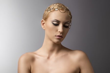 portrait of blonde girl with golden jewellery on the head, she looks down at leftの写真素材