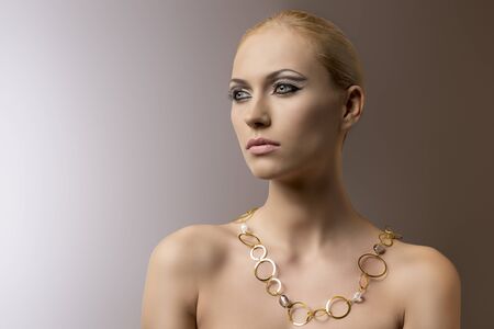 pretty blonde girl with necklace rings, her face is turned of three quarters at right and looks in front of herの写真素材