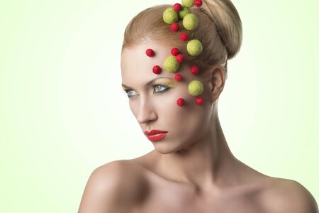 blonde girl with red and green balls on the faceの写真素材