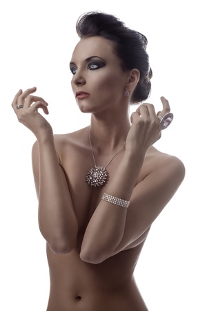 sexy young girl with brown hair and nude body covering her breast with arms and wearing some silvery jeweleryの写真素材