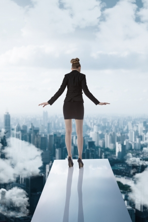 blonde business woman on trampoline wearing formal suit turned on her back  and looking downの写真素材