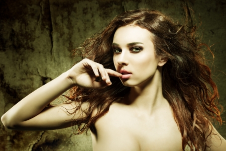 sexy girl with long brown flying hair and elegant make-up in sensual pose with fashion color and grunge backgroundの写真素材