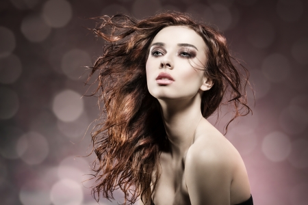 fashion portrait of beauty brunette girl with wavy, flying wet hair. Posing with sensual expression and and cute make-up on flare backgroundの写真素材