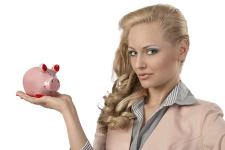 close-up portrait of blonde girl with business suit and curly hair-style taking pink piggybank in the hand and looking in the cameraの写真素材