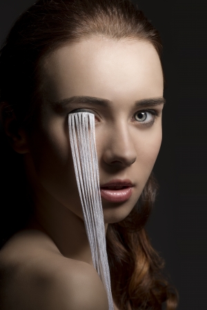 sensual brunette girl in beauty portrait with creative make-up and long eyelashes falling on her face. Looking in camera on black backgroundの写真素材