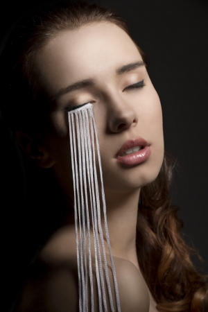 close-up portrait of sensual girl with creative make-up and long eyelashes falling on her shoulder. On black backgroundの写真素材
