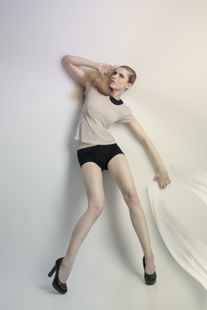 sensual blonde woman posing in fashion portrait with creative hair-style and cute make-up  She wearing pois shirt, sexy shorts and black heels の写真素材