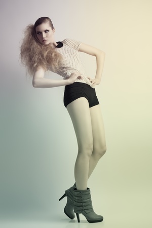 amazing blonde woman in fashion pose with creative hair-style and cute make-up  She wearing boots, pois shirt and sexy black shorts の写真素材